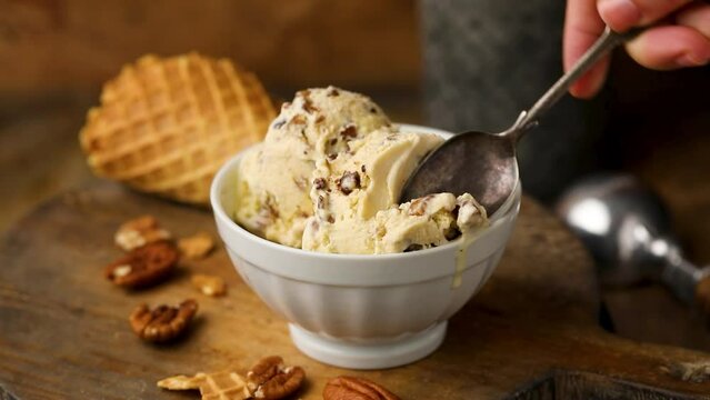 Butter pecan ice cream with candied pecan pieces being eaten with a spoon