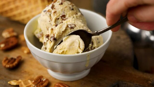 Butter pecan ice cream with candied pecan pieces being eaten with a spoon