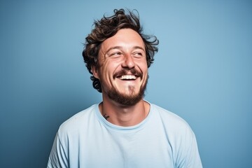 Portrait of a funny young man laughing on a blue background.