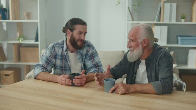 Two friends, a young man and an older man, are sitting at a table, discussing life situations and providing each other with psychological support, friendly communication, intergenerational dialogue