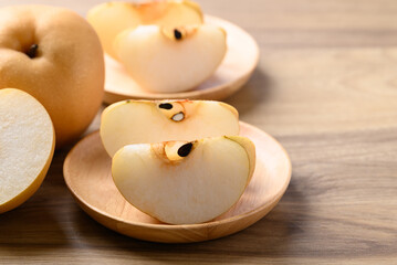 Piece of Asian pear fruit or Nashi pear on wooden plate ready to eating