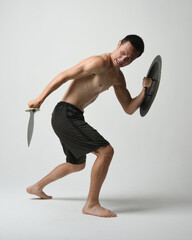 Full length portrait of fit handsome shirtless asian male model,  Holding sword weapon and Spartan...