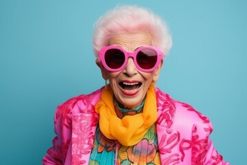Portrait of a happy senior woman with pink sunglasses on blue background