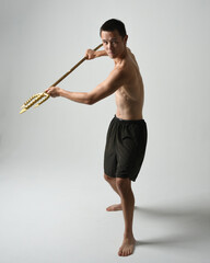 Full length portrait of fit handsome shirtless asian male model,  Holding golden trident weapon,...