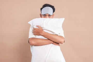 Man with blindfold on his forehead, hugging his pillow, ready for falling asleep 