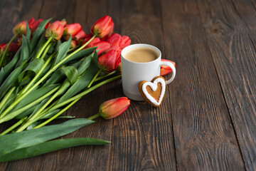 Fresh orange tulips and cappuccino mug with spring composition. Greeting card with copy space for Valentine's Day, Woman's Day and Mother's Day.