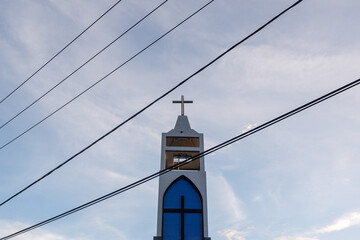 Roof of church with holy cross. Cloudy blue sky background Photo of cross on the church. Alfa Omega church Raja Ampat
