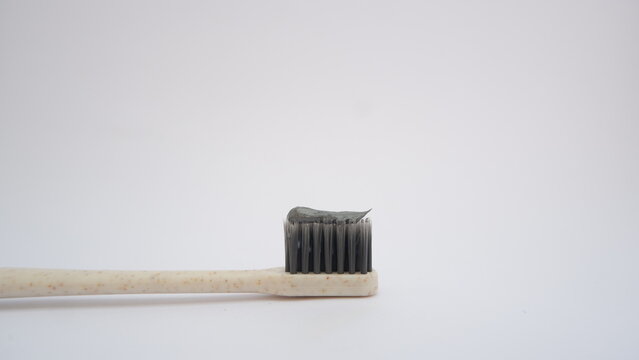 Close up toothbrush with toothpaste on white background. Gray toothbrush bristles. Selective focus. Teeth care concept.