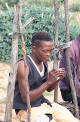 young african man with a tough figure rolling a joint of marijuana, ghetto township south africa ,...