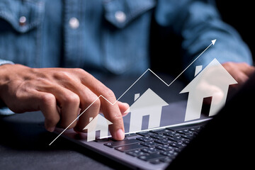 Real estate investment concept. Person using laptop with house icon and growth graph. Analyzing...