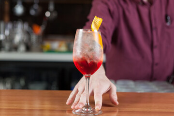Bartender making a fruity summer cocktail at a bar. 