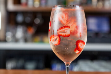 Bartender making a fruity summer cocktail at a bar. 