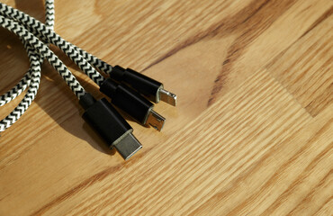 Three types of phone charger 3-in-1 cable connector on wooden desk