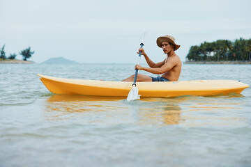 Summer Fun Kayaking on a Tropical Beach: Active Asian Man Enjoying Water Sports and Leisure Vacation