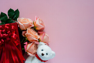 Pink roses in red gift box with white teddy bear doll on pink background for Valentines day concept.
