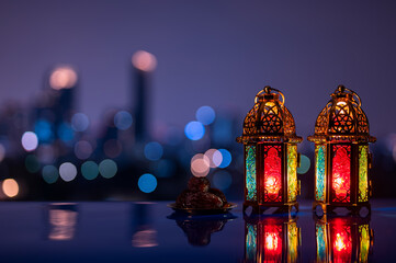 Two lanterns and small plate of dates fruit with night sky and city bokeh light background for the Muslim feast of the holy month of Ramadan Kareem.