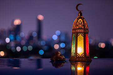 Lantern and small plate of dates fruit with night sky and city bokeh light background for the Muslim feast of the holy month of Ramadan Kareem.