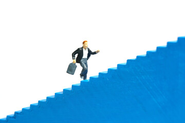 Miniature people toy figure photography. A boy pupil student running on staircase. Isolated on a...