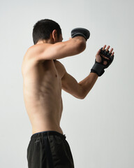 Close up portrait of fit  asian male model, shirtless with muscles. Wearing gym shorthand boxing gloves, gestural punching pose. Isolated on a white studio background. - obrazy, fototapety, plakaty