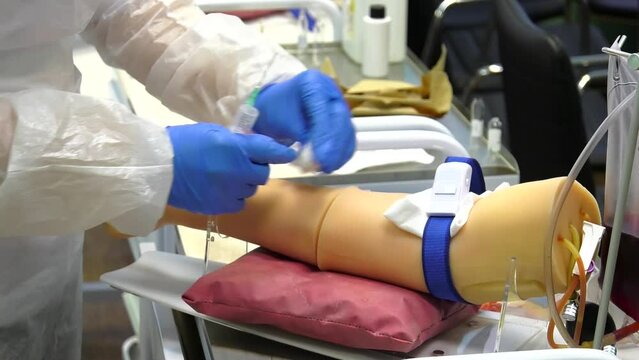 Woman makes an injection in the arm of a mannequin. Hand of a medical plastic mannequin for the practice and training of young doctors on a simulator.