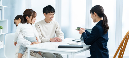 住宅の模型を見て話す親子と営業をする女性