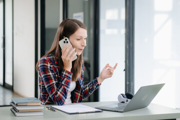 Beautiful woman using laptop and tablet while sitting at her working place. Concentrated