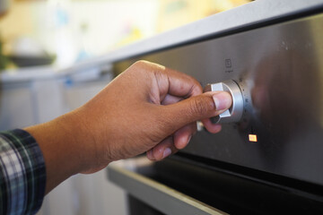 Close up of men hand setting temperature control on oven.