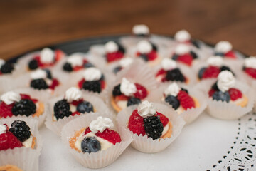 Close up of mini puff tartlets topped with berries and whipped cream