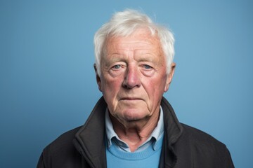 Portrait of senior man with grey hair looking at camera over blue background