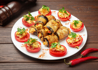 Appetizer: stuffed eggplants and tomatoes. On a wooden background.