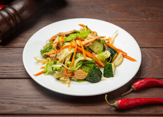 Salad of chicken, lettuce, carrots and cucumbers. On a wooden background.