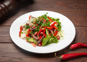 Salad with meat and beans. On a wooden background.