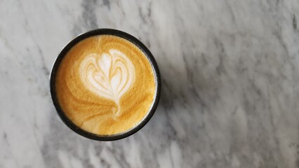 Top view of a cup of cappuccino on a marble table with negative space to the right of the object