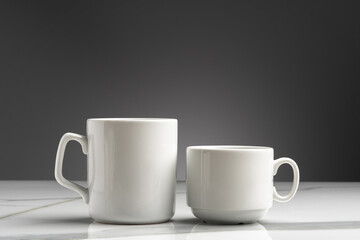 Ceramic cups on marble table against gray background