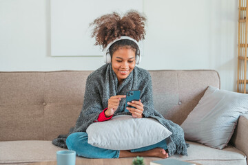 African American teenage women sitting on sofa listening to music enjoying meditation for sleep and...
