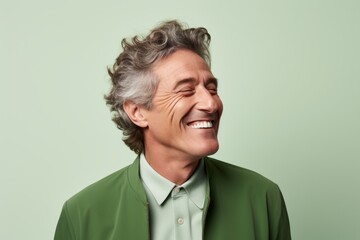Handsome middle aged man laughing and looking up on green background