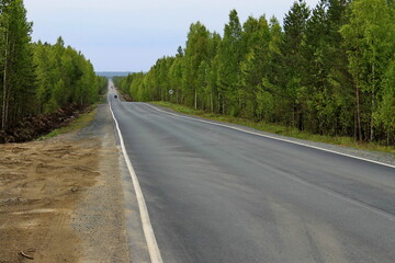 Fototapeta na wymiar An asphalt road leading to the horizon through the forest. Republic of Karelia, Russia.