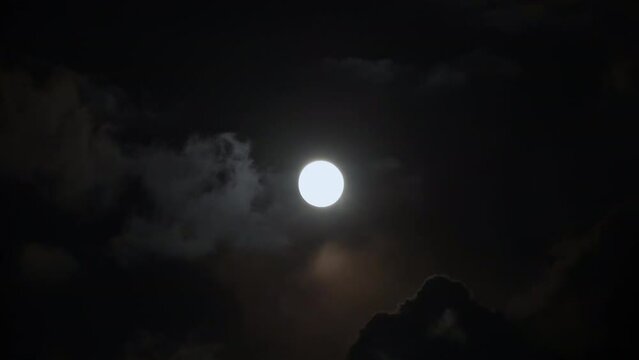 Shining full moon on a cloudy sky at night, shot of a sky at night with full moon and clouds