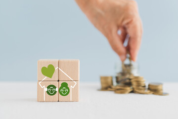 Obraz premium Planning money saving for retirement, investment for expense after retire life. Pension insurance, life insurance concept. Old persons inside house on wooden blocks and blurred hand arranged coins