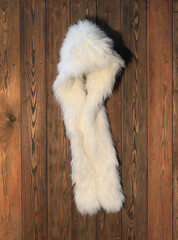 white fur hat on a hanger on a wooden wall