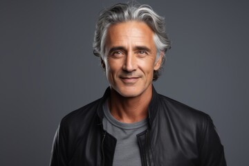 Portrait of a handsome middle-aged man in black leather jacket, over grey background.