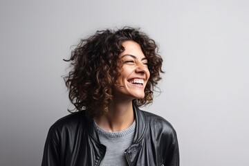 Fototapeta na wymiar Happy young woman with long curly hair laughing and looking up over grey background
