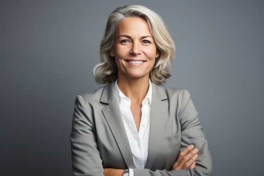 Confident businesswoman. Confident mature businesswoman looking at camera and smiling while standing against grey background