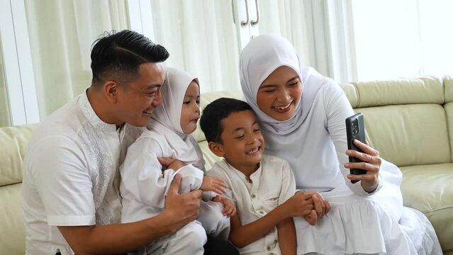 Happy muslim family making a video call by using a cellphone while sitting together
