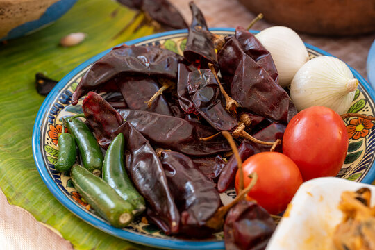 Chile jalape&ntilde;o, chile guajillo, jitomates y cebollas juntos en un plato