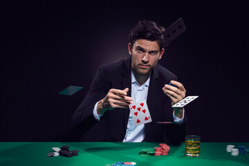 Games Addiction Ideas. Emotional Handsome Caucasian Brunet  Pocker Player At Pocker Table With Chips and Cards Throwing Cards Playing and Drinking Alcohol.