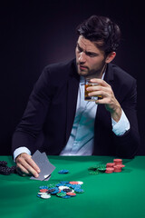 Games Addiction Ideas. Emotional Handsome Caucasian Brunet  Pocker Player At Pocker Table With Chips and Cards Playing and Drinking Alcohol.