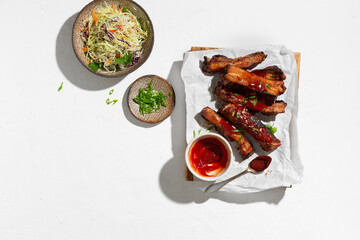 Spicy grilled ribs with green onions and cole slaw salad. White background, Top view, flat lay.