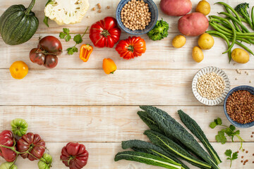 Seasonal vegetables, corn, potatoes, tomatoes, various peppers on a wooden background. Top view.