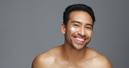 Face, cream and man with skincare, dermatology and beauty with glow on a grey studio background....